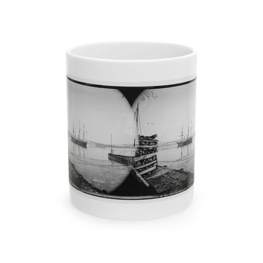 Black and white stereo view of ships at anchor in a calm harbour, a wharf stacked with cordwood in front.