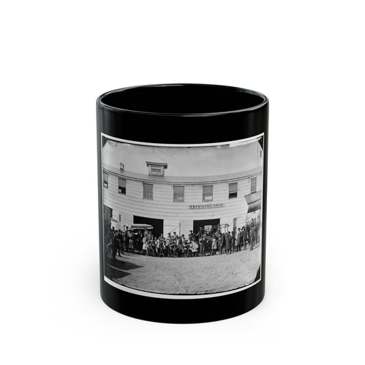 Black and white 1860s scene of a crowd of men before a two-storey wooden building with wagons at its doors.