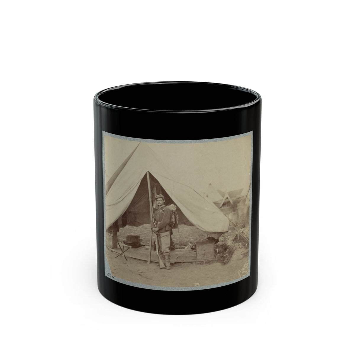 Sepia print of a soldier with a rifle and knapsack standing beside a large canvas tent in a military camp.