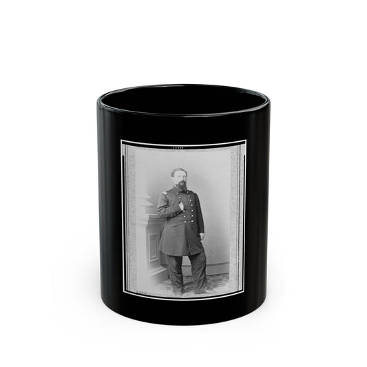 Black and white studio portrait of a standing bearded officer in a long coat with rows of buttons, beside a column.