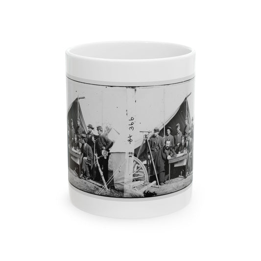 Black-and-white stereo view of uniformed men around a field table before a canvas tent, with a surveying tripod.