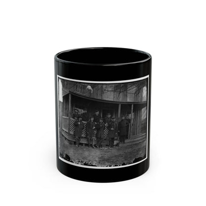 Black-and-white view of ten uniformed officers in caps and coats posed on the porch of a wooden house.