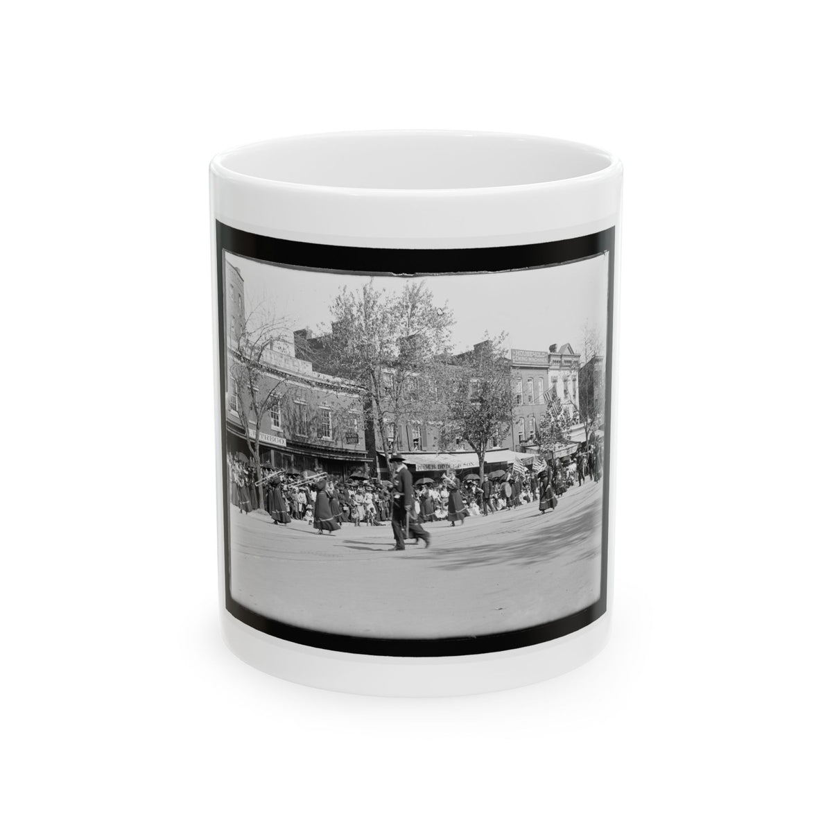 Black-and-white street scene of a parade of women with brass instruments and a crowd under umbrellas.