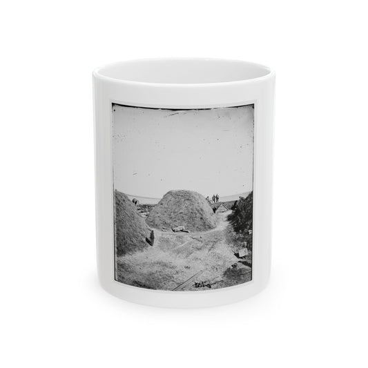 Black and white view of grassy earthen mounds and a dirt path inside a fort, with small figures on the rampart.