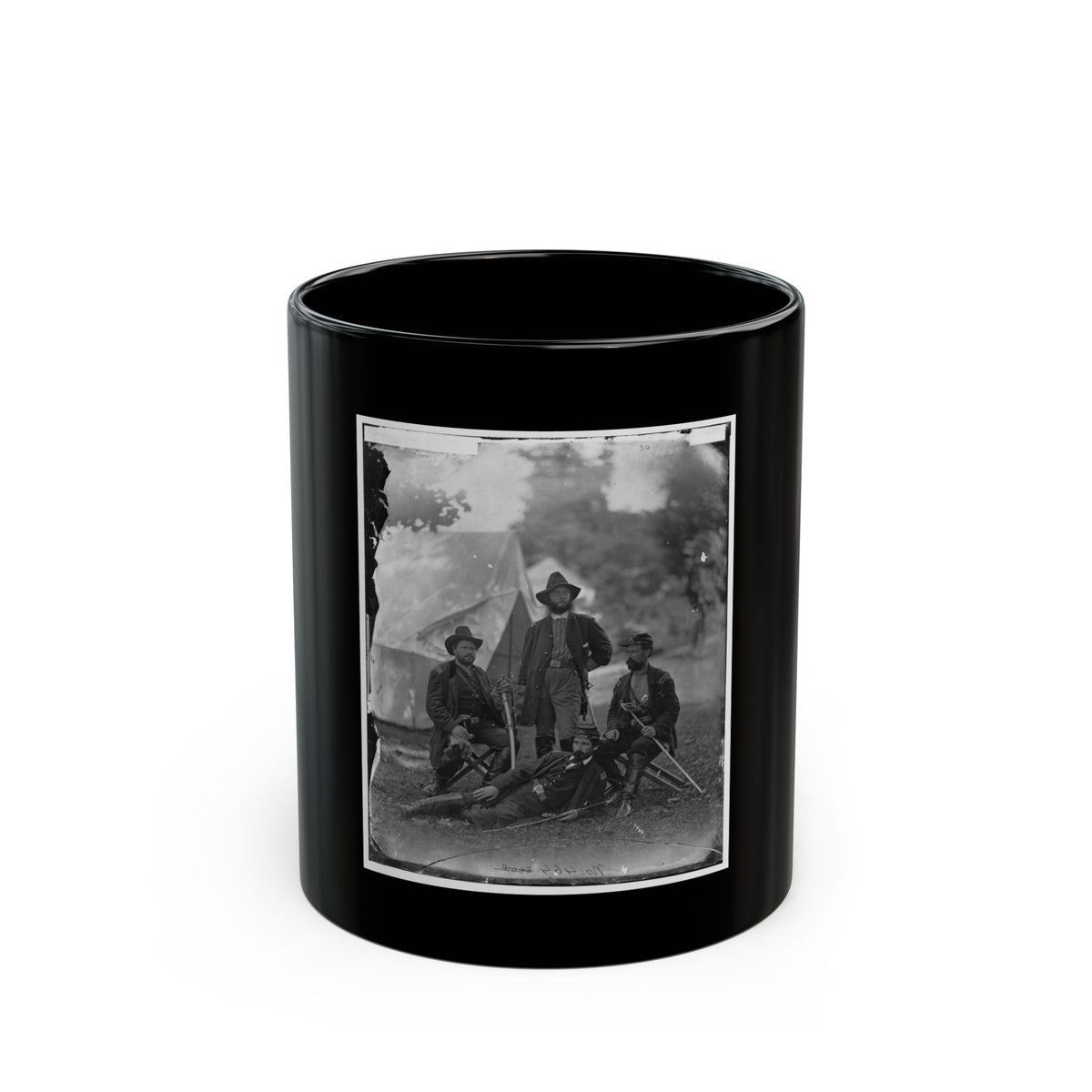 Black and white portrait of four uniformed soldiers in a grassy camp before a canvas tent, one reclining with a rifle.