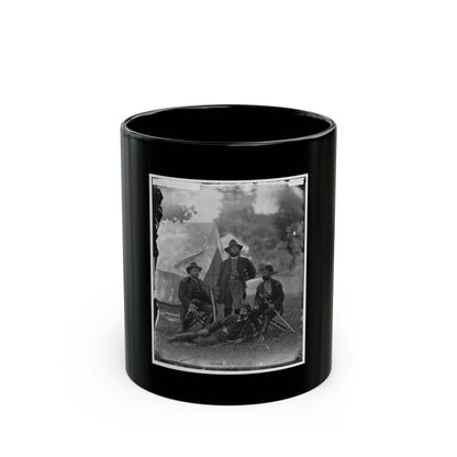 Black and white portrait of four uniformed soldiers in a grassy camp before a canvas tent, one reclining with a rifle.