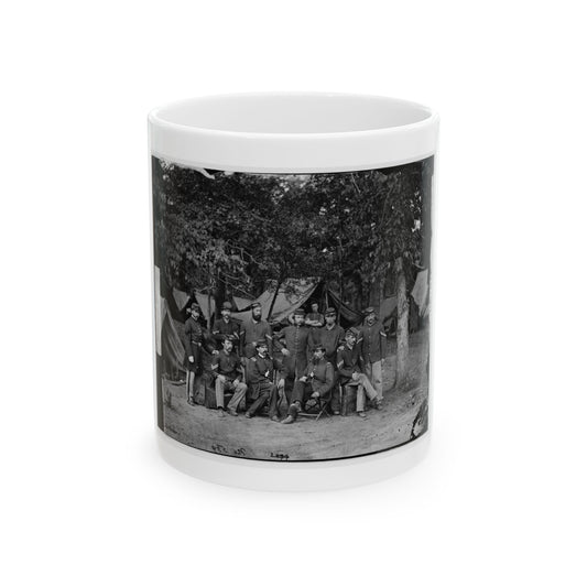 Black and white group print of about eleven uniformed soldiers posed in a wooded camp near canvas tents.