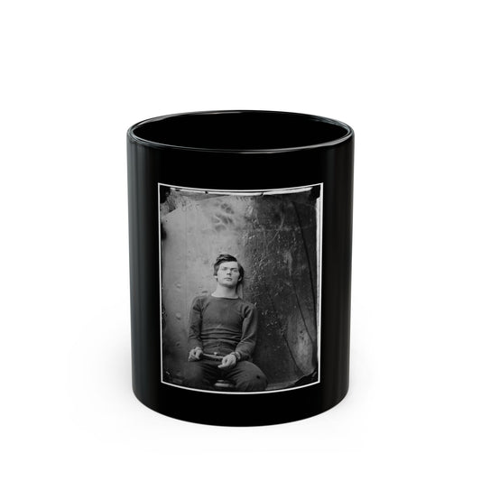 Black and white 1860s studio portrait of a young man in a dark knit sweater, hands clasped, against a textured backdrop.