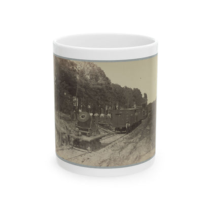 Sepia print of railroad workers beside a steam locomotive and boxcar passing through a pine forest.