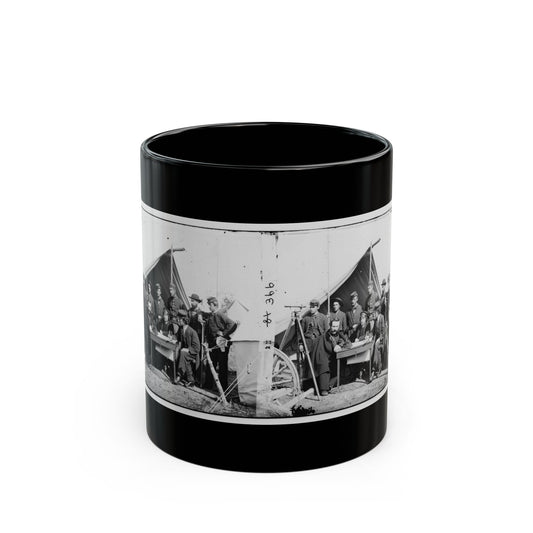 Black-and-white stereo view of uniformed men around a field table before a canvas tent, with a surveying tripod.