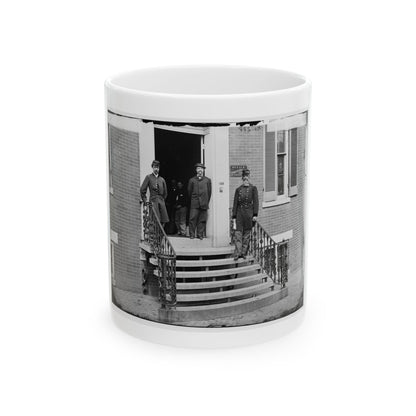 Black and white 1860s view of men in uniform and civilian dress on ornate iron steps of a brick office building.